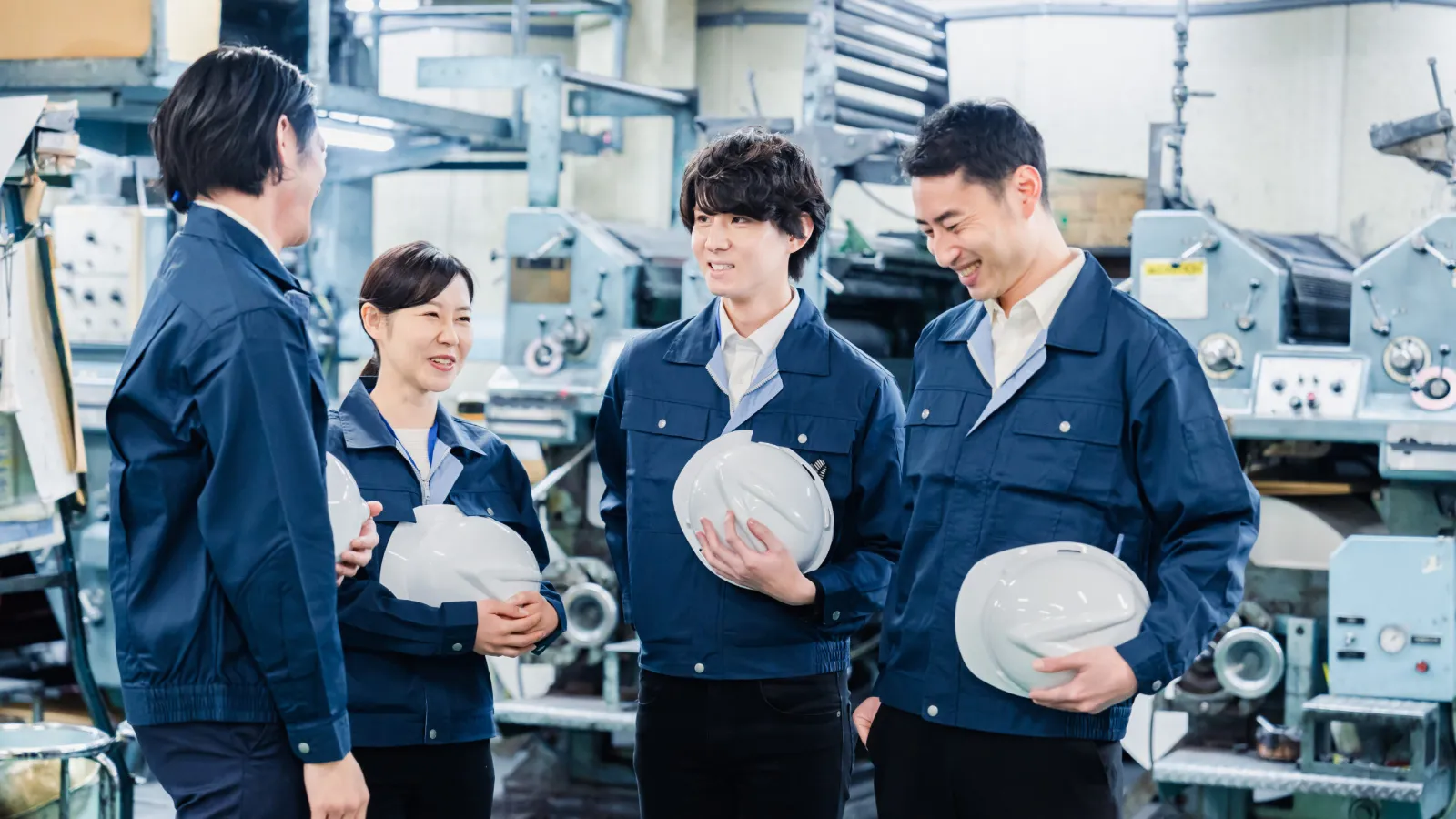 工場内で会話をする若手社員と作業スタッフ